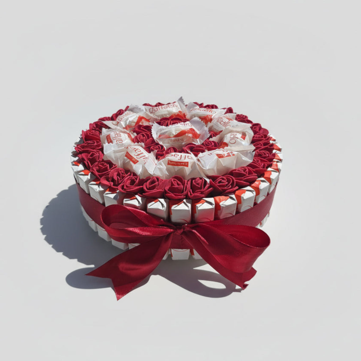 Coffret cadeau bouquet de chocolats Raffaello avec fausses roses rouges. Boîte ronde de gourmandises et décoration Saint-Valentin, fête des mères ou anniversaire. Ruban satin rouge.