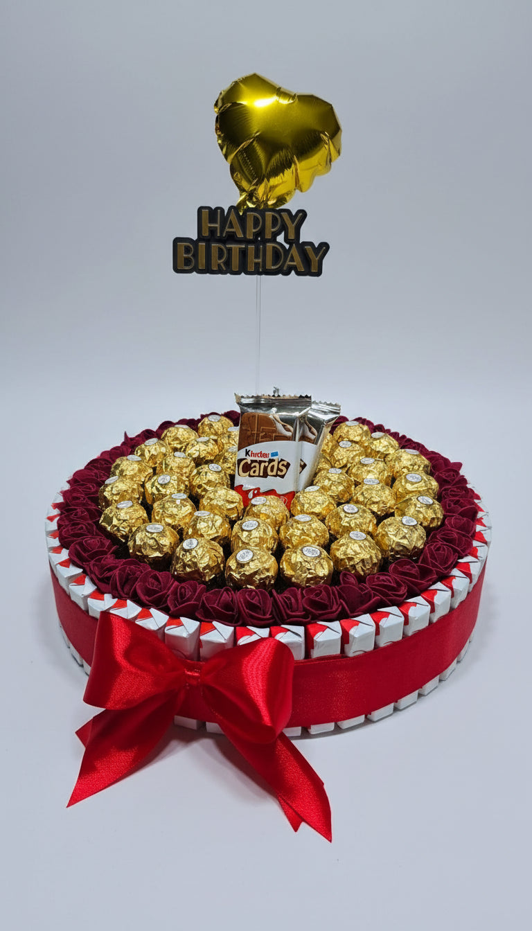 Gâteau de chocolats ou boîte cadeau ronde Ferrero Rocher et Kinder Cards. Décoration avec roses bordeaux et topper "Happy Birthday" doré. Idée cadeau d'anniversaire festif.